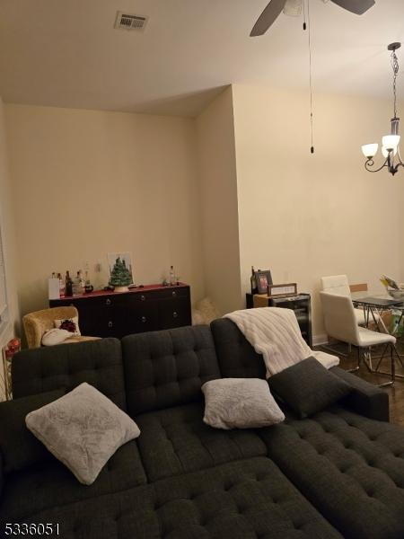 living room featuring visible vents and ceiling fan with notable chandelier