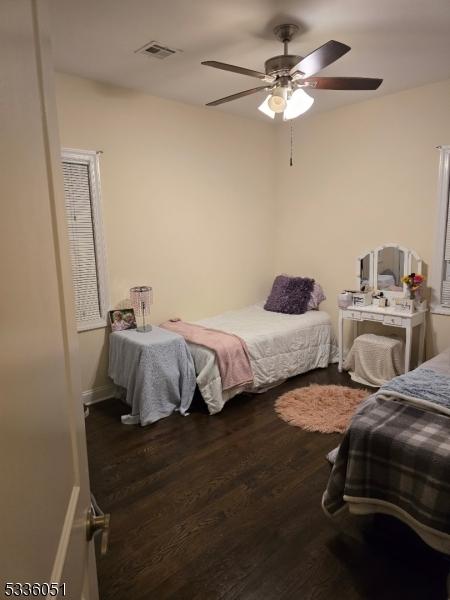 bedroom with ceiling fan, visible vents, and dark wood-type flooring