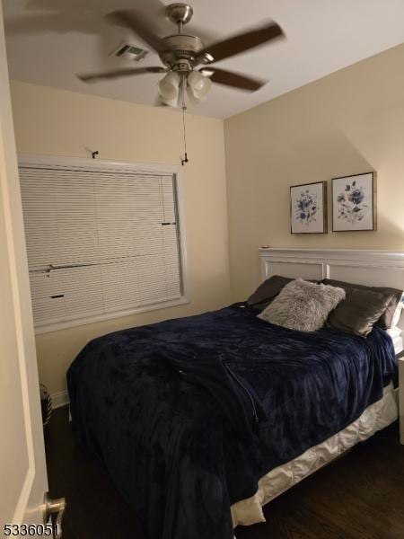 bedroom featuring a ceiling fan, visible vents, and wood finished floors