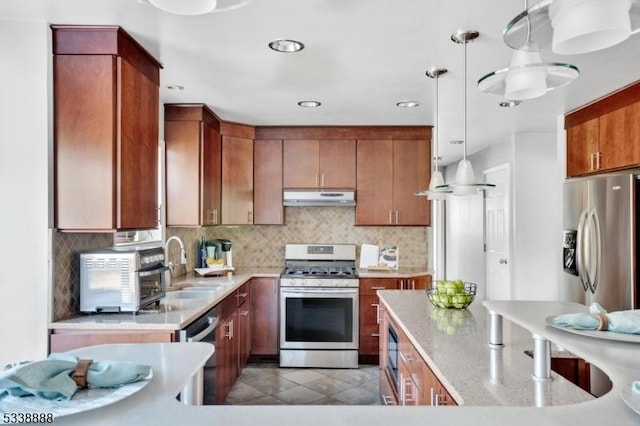 kitchen with stainless steel appliances, pendant lighting, under cabinet range hood, and backsplash