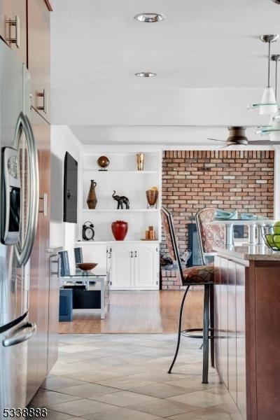 kitchen featuring pendant lighting, light countertops, stainless steel refrigerator with ice dispenser, white cabinetry, and open shelves