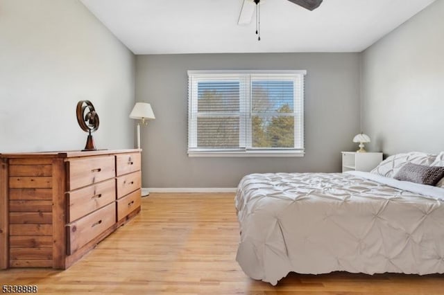 bedroom with ceiling fan, light wood-style flooring, and baseboards