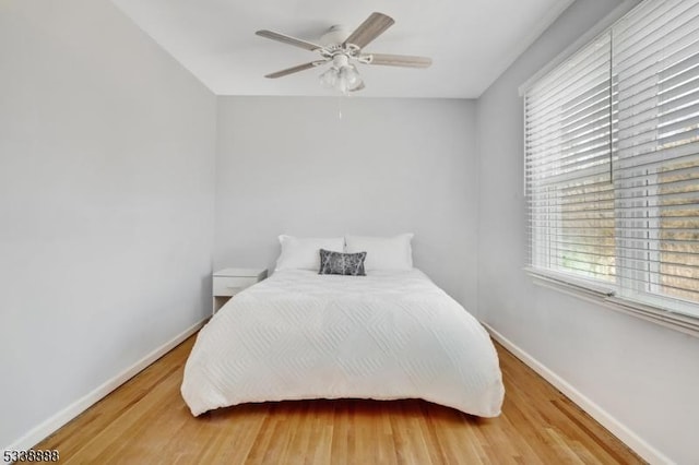 bedroom with wood finished floors, a ceiling fan, and baseboards