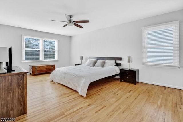 bedroom with light wood-style floors, baseboards, and a ceiling fan