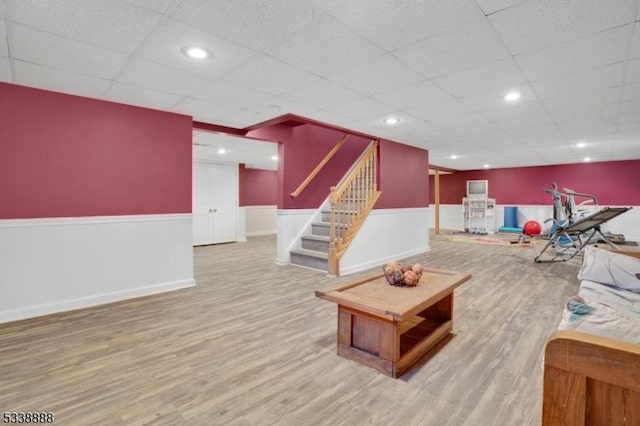 living area featuring a wainscoted wall, recessed lighting, stairway, wood finished floors, and a drop ceiling