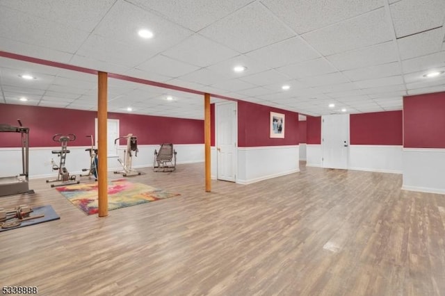 exercise room with recessed lighting, wainscoting, a drop ceiling, and wood finished floors