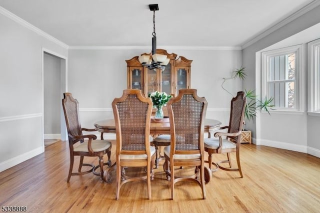 dining area with a chandelier, ornamental molding, wood finished floors, and baseboards