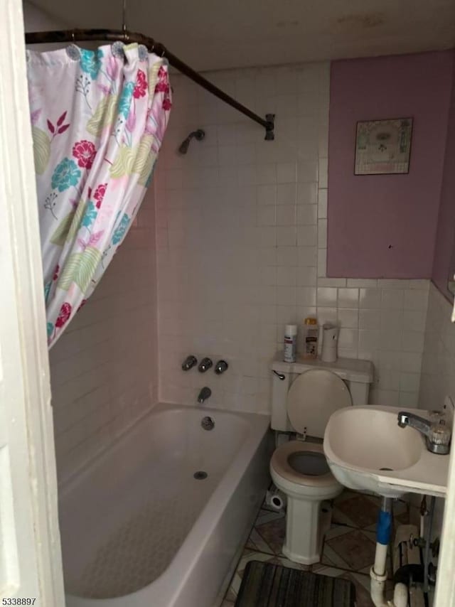 bathroom featuring toilet, shower / tub combo, a sink, and tile walls