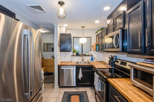 kitchen with butcher block countertops, a sink, visible vents, appliances with stainless steel finishes, and pendant lighting