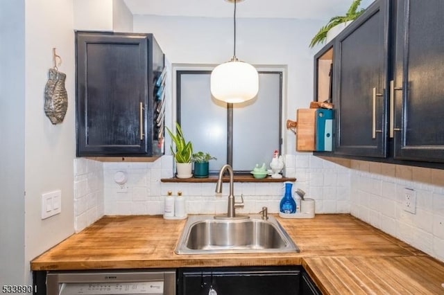 kitchen featuring hanging light fixtures, a sink, wood counters, and dishwashing machine