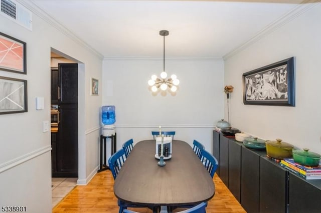 dining space with a chandelier, visible vents, crown molding, and light wood finished floors