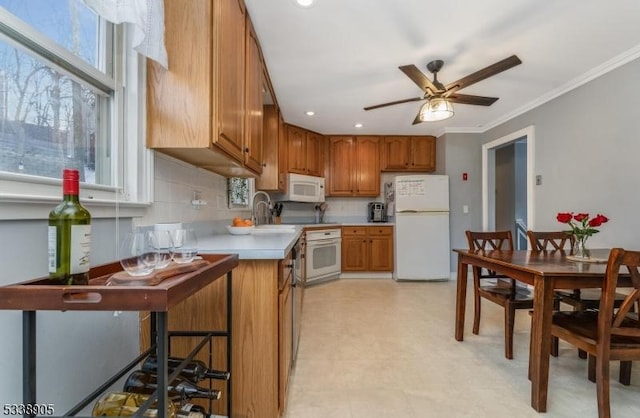 kitchen with sink, ornamental molding, white appliances, ceiling fan, and decorative backsplash