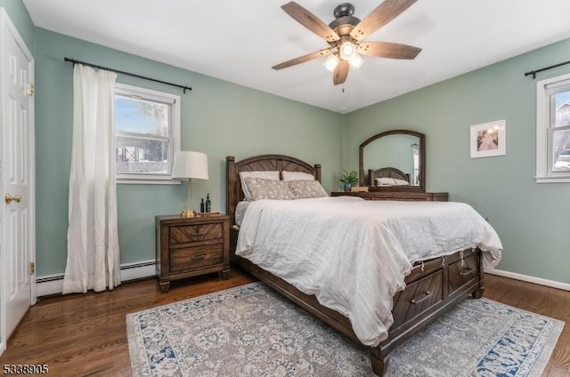 bedroom with multiple windows, baseboard heating, dark wood-type flooring, and ceiling fan