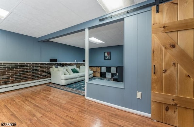 living room with wood-type flooring, a baseboard heating unit, a barn door, and beam ceiling