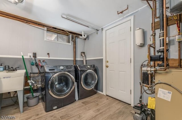 clothes washing area featuring light hardwood / wood-style floors and washer and clothes dryer