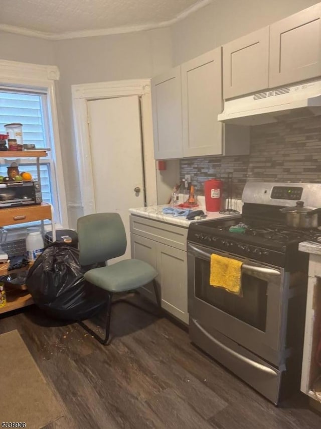 kitchen with decorative backsplash, dark wood finished floors, gas range, and under cabinet range hood