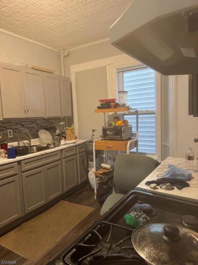 kitchen featuring light countertops, gray cabinetry, decorative backsplash, a sink, and black microwave