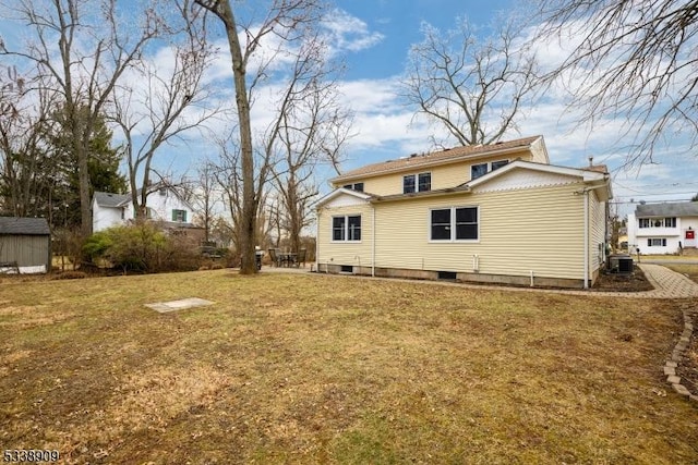 rear view of property with central AC unit and a lawn