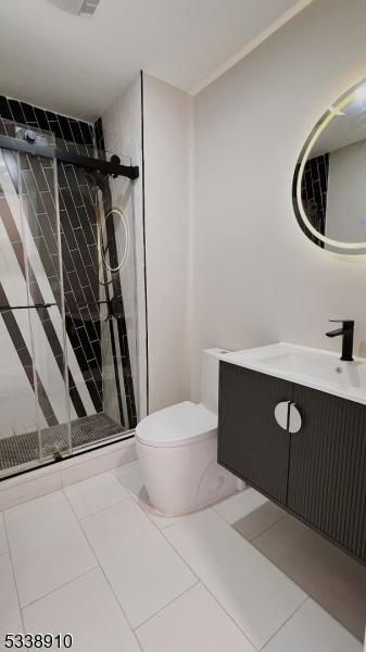 bathroom with tile patterned floors, toilet, vanity, and an enclosed shower