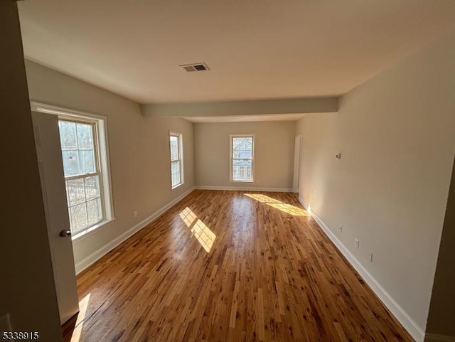 unfurnished room with visible vents, baseboards, and wood finished floors