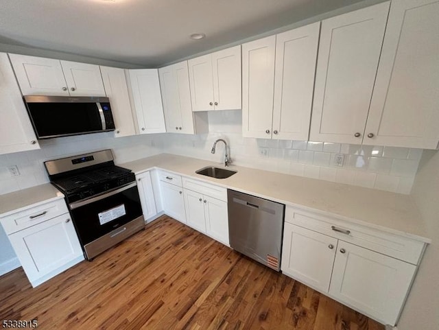 kitchen featuring light countertops, appliances with stainless steel finishes, a sink, and white cabinetry