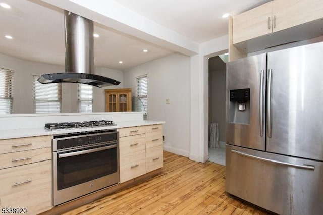 kitchen featuring appliances with stainless steel finishes, light hardwood / wood-style floors, light brown cabinets, and island exhaust hood