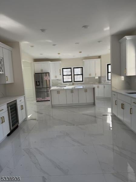 kitchen featuring white cabinetry, stainless steel fridge with ice dispenser, wine cooler, and a wealth of natural light