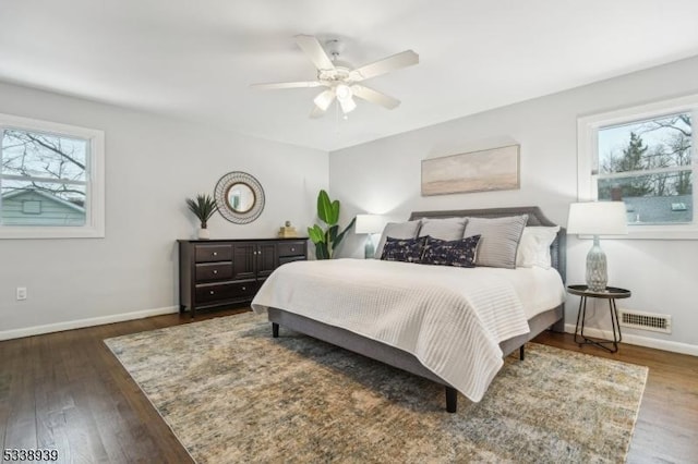 bedroom featuring ceiling fan, multiple windows, and dark hardwood / wood-style floors