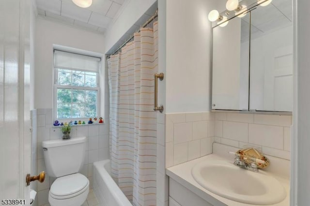 full bathroom with shower / tub combo with curtain, toilet, tile walls, and vanity