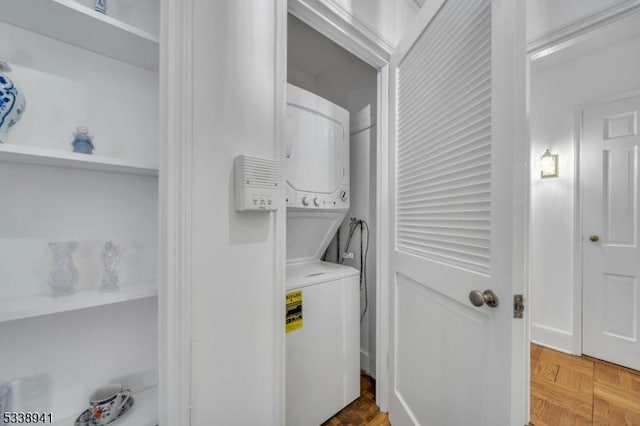 washroom featuring stacked washer and dryer and parquet floors