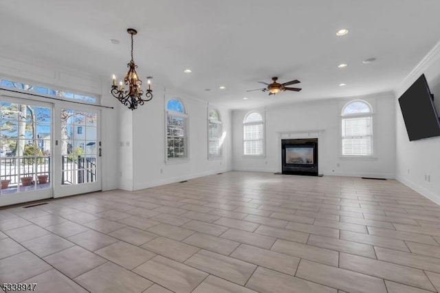 unfurnished living room featuring a glass covered fireplace, a healthy amount of sunlight, baseboards, and ceiling fan with notable chandelier