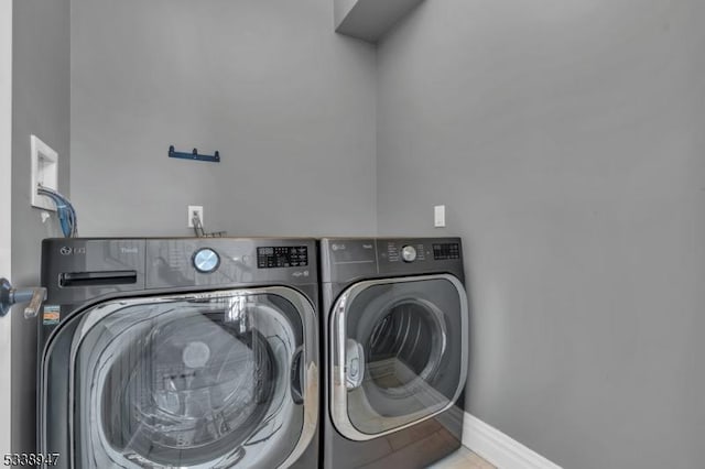 clothes washing area featuring laundry area, washer and clothes dryer, and baseboards