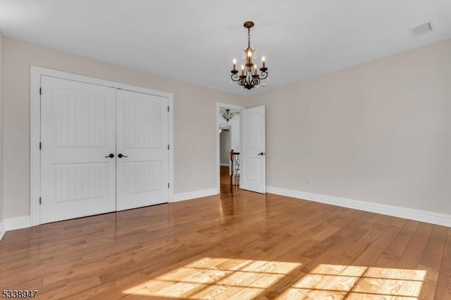 interior space featuring a notable chandelier, a closet, visible vents, light wood-style floors, and baseboards