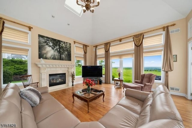 living room featuring a chandelier, visible vents, high vaulted ceiling, and light wood finished floors