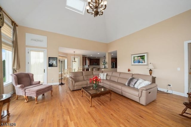 living area with light wood-type flooring, a towering ceiling, and an inviting chandelier