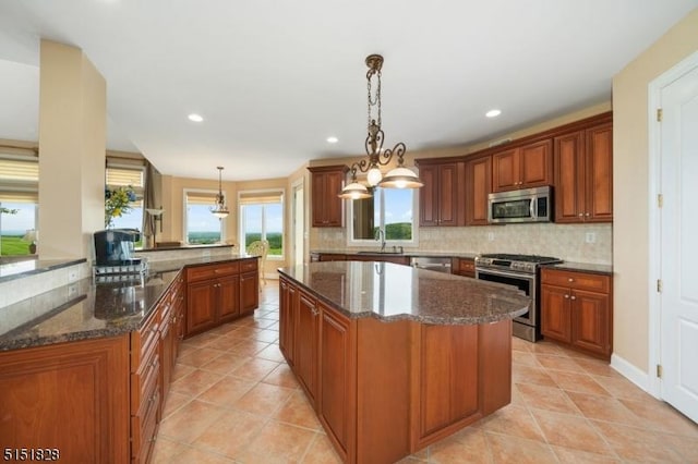 kitchen featuring stainless steel appliances, backsplash, a kitchen island, and a sink