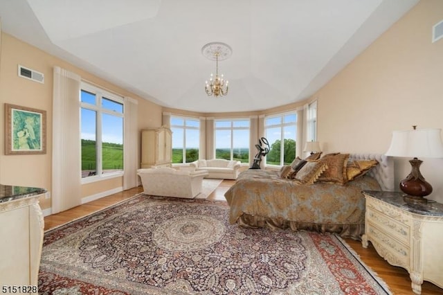 bedroom with a chandelier, multiple windows, wood finished floors, and visible vents