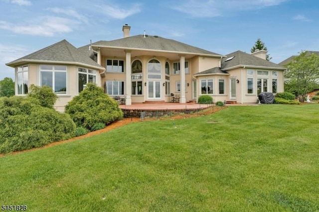 back of house with a patio, a lawn, a chimney, and stucco siding