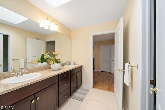 bathroom with double vanity, a skylight, visible vents, and a sink