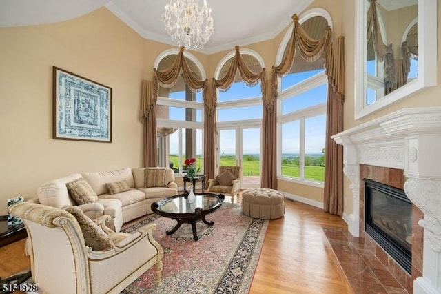 living area with a chandelier, a high ceiling, a fireplace, light wood finished floors, and crown molding