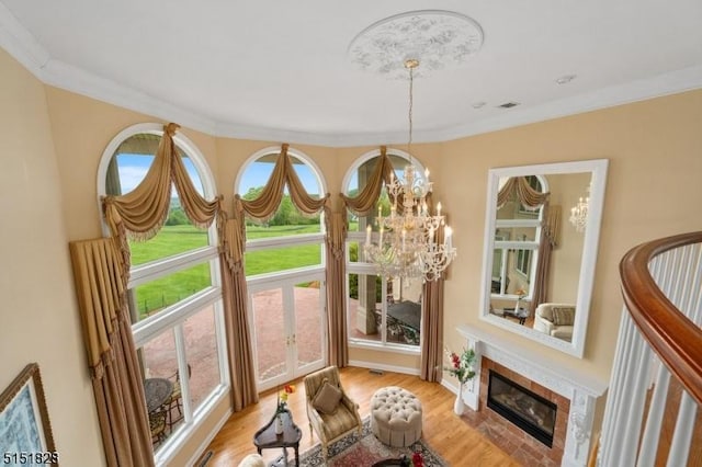 interior details featuring a fireplace with flush hearth, crown molding, an inviting chandelier, and wood finished floors