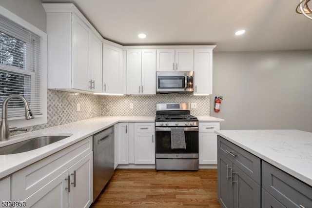 kitchen with white cabinets, gray cabinets, stainless steel appliances, and a sink