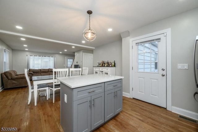 kitchen with pendant lighting, visible vents, gray cabinetry, open floor plan, and wood finished floors