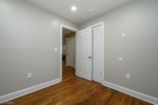 spare room with baseboards, visible vents, and wood finished floors