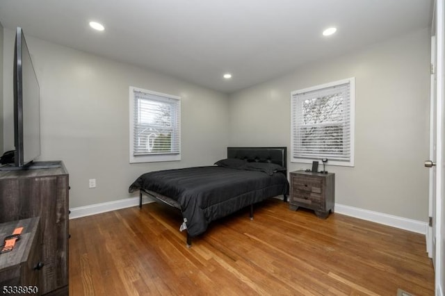 bedroom with recessed lighting, wood finished floors, and baseboards