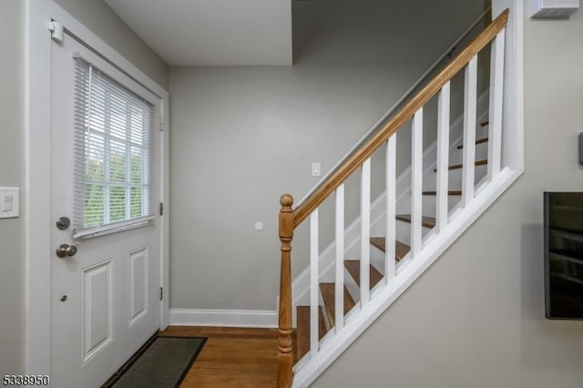 entryway with dark wood-style floors, stairs, and baseboards