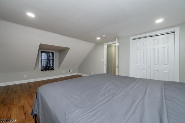 bedroom with dark wood-style floors, recessed lighting, a closet, lofted ceiling, and baseboards