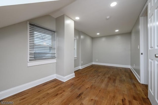 interior space featuring dark wood-type flooring, recessed lighting, lofted ceiling, and baseboards