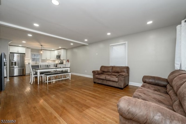 living area with light wood-type flooring, baseboards, and recessed lighting