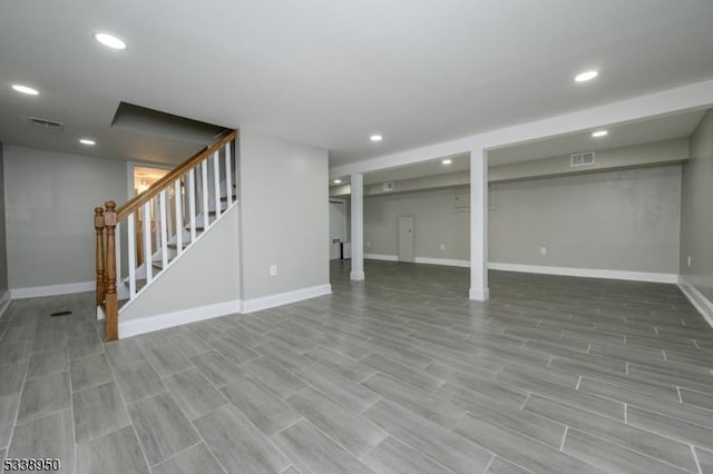 finished basement featuring visible vents, stairway, baseboards, and recessed lighting